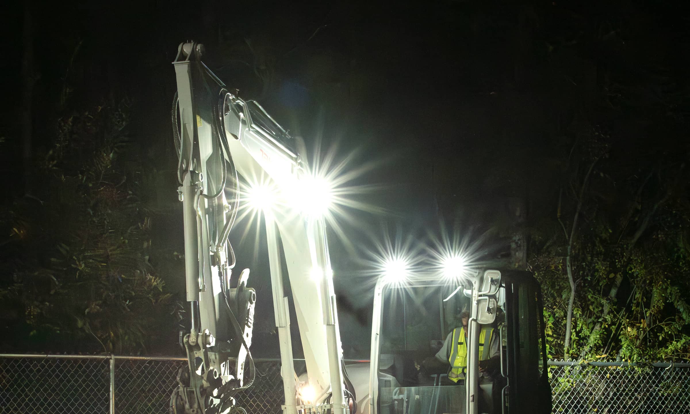 An excavator working under its own lights on a night dig